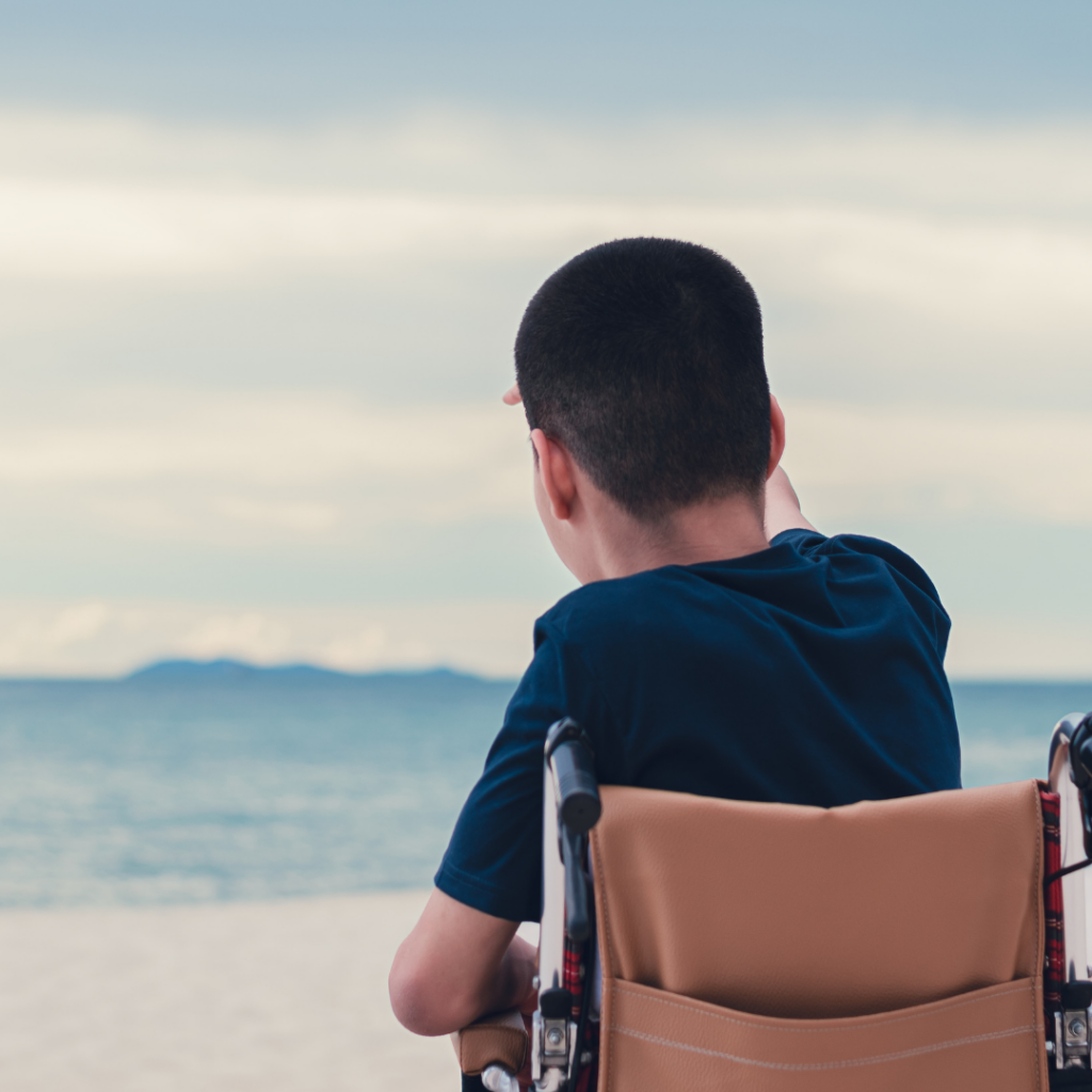 Child in wheelchair looking to beach