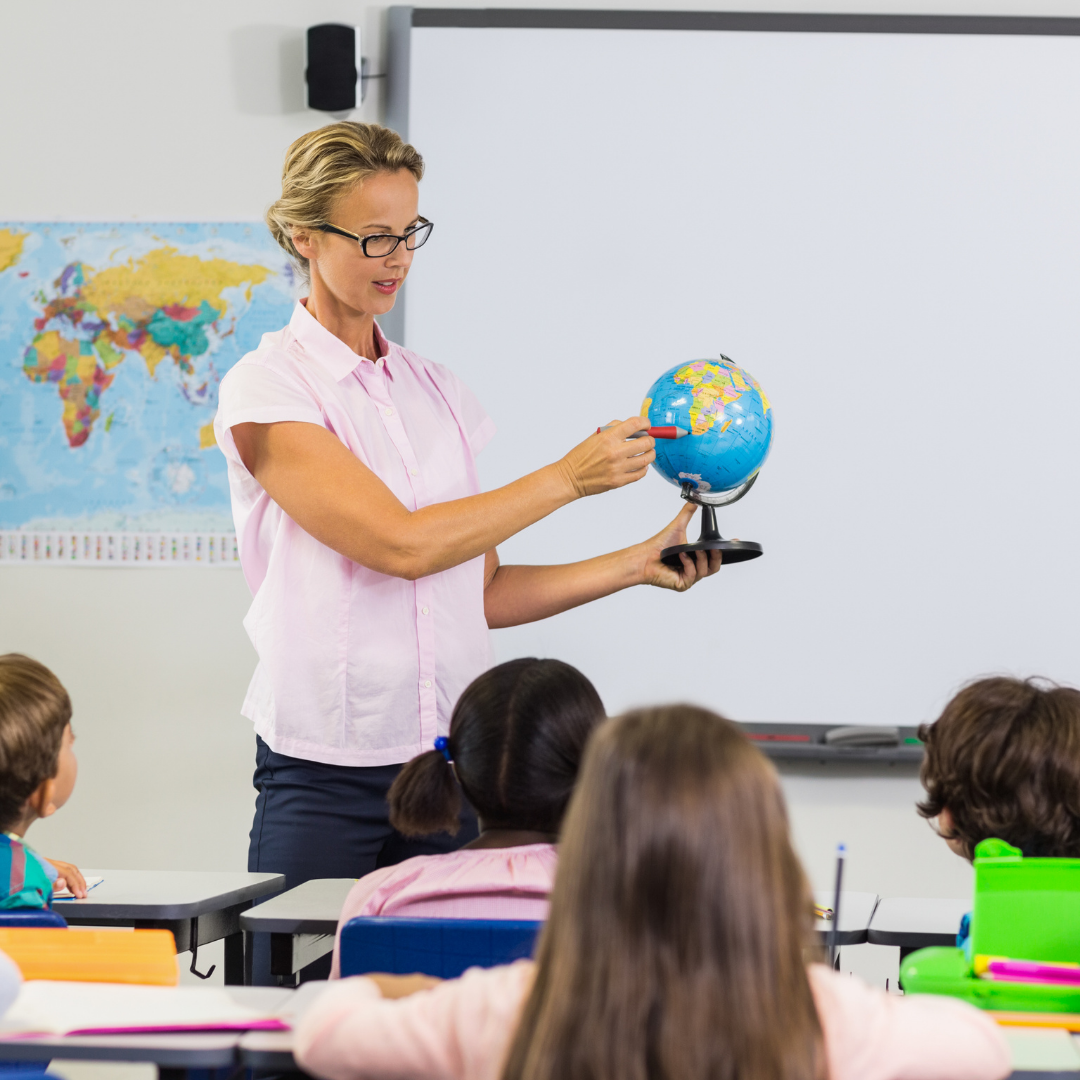 Teacher pointing at a globe with students
