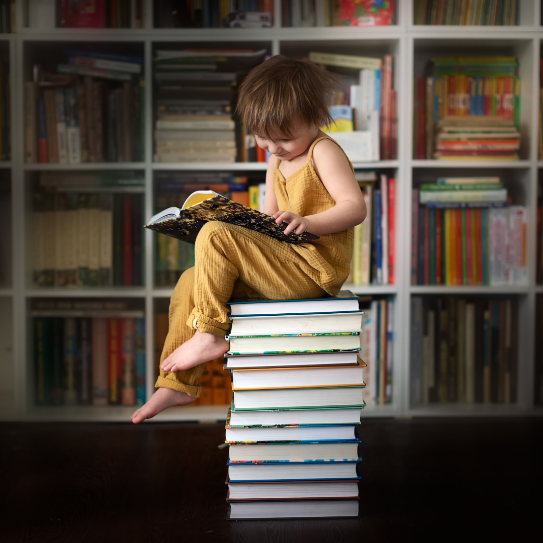 girl reading sitting on a stack of books