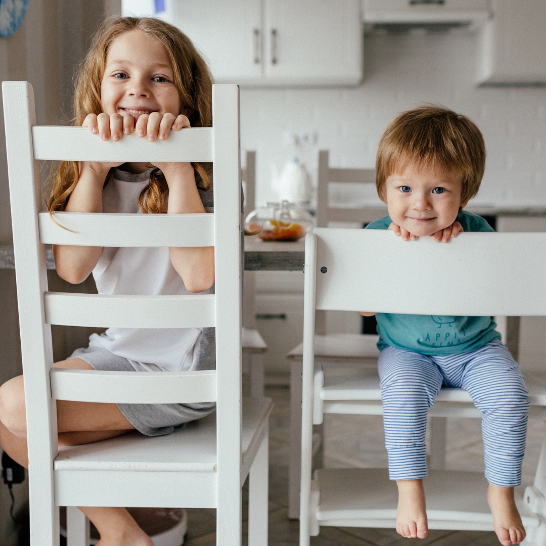 siblings sitting on chairs on the kitchen