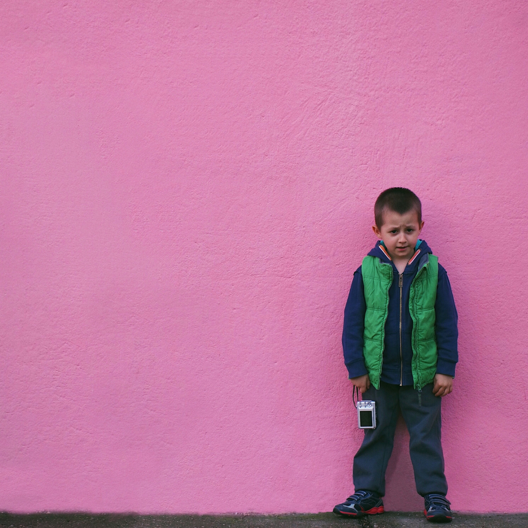 A child standing in front of a pink wall