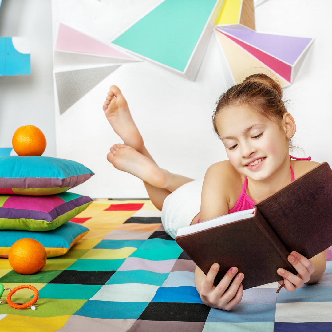 A young girl reading a book on the floor